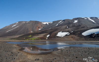 At Hungurfit with colorful mountains and small lake in front. Neon green moss and volcanic sand in front.