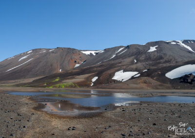 At Hungurfit with colorful mountains and small lake in front. Neon green moss and volcanic sand in front.