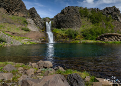 Waterfall in Lava cliffs with lake in front called Gjáin