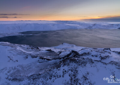 Lake seen over mountains in winter with snow on top in the morning twilight