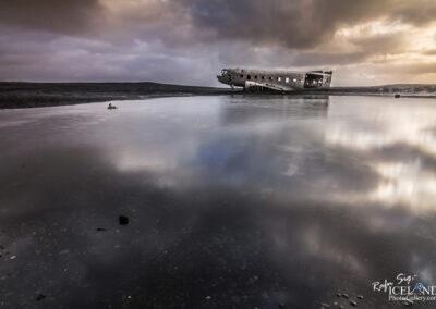 A Airplane wrack floats on the calm waters of a picturesque lake in Iceland, surrounded by stunning natural beauty.