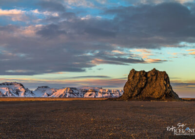 A solitary rock formation emerges from the barren desert terrain of Iceland, illustrating the area's dramatic geological features.