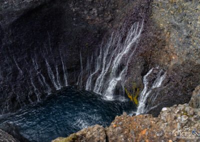 A majestic waterfall tumbles out of a rocky cliff in Iceland, highlighting the region's breathtaking scenery.