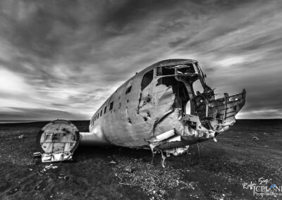 An Aircraft wreck stands alone in the black sand beach in Icelandic wilderness, blending history with the serene rural landscape.