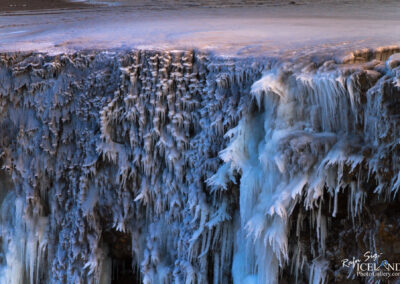 Frozen water descends from a cliff's edge, capturing the essence of winter's chill and natural artistry in Iceland