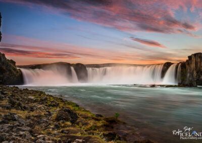 A stunning sunset illuminates the falls in Iceland, creating a picturesque scene of nature's beauty.