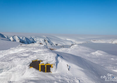 A small cabin covered in snow, nestled in the icy landscape of Iceland's glacier - volcano region.