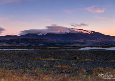 A majestic volcano in Iceland rises against a backdrop of a cloud-filled sky, showcasing nature's grandeur.