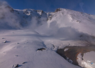 A stunning snow-covered mountain emitting steam, highlighting the beauty of winter's chill and geothermal activity.