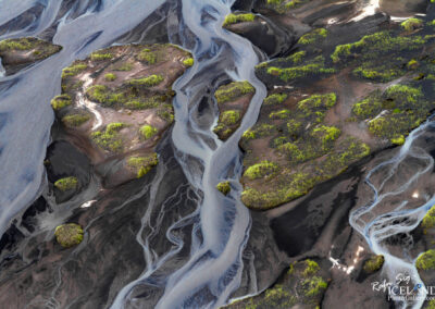 A picturesque river winds through a rocky area, illustrating the harmony of water and rugged geology in the Icelandic landscape.