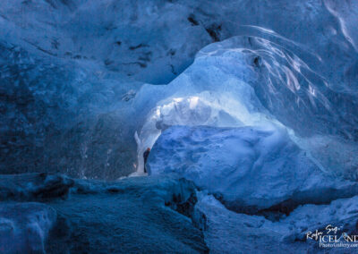 An enchanting blue ice cave featuring a warm light glowing from inside, highlighting the cave's icy textures.