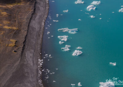 A serene scene of icebergs floating in tranquil waters, highlighting their stunning shapes and icy textures outside from the black beach.