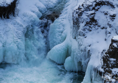 A stunning waterfall in Iceland, completely covered in ice and snow, showcasing nature's winter wonderland.