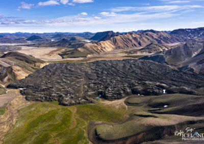 A stunning valley view in Iceland, with majestic mountains and a verdant field set against a backdrop of volcanic lava.