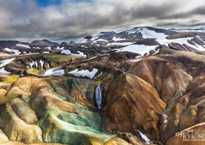 A picturesque scene of Iceland's colorful mountains, highlighted by a serene waterfall flowing through the vibrant terrain