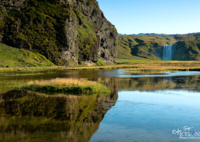 A picturesque mountain scene showcasing a waterfall cascading down, set against a backdrop of rich, green vegetation and a small lake