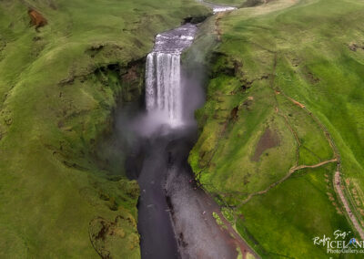 Scenic aerial shot of a powerful waterfall in Iceland, showcasing its natural beauty amidst the dramatic landscape.