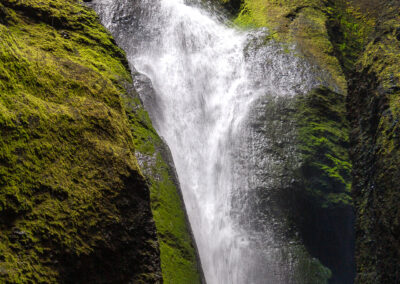 Overhead perspective of a majestic waterfall in Iceland, flowing powerfully amidst dramatic landscapes and vibrant nature.