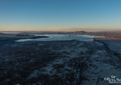 Aerial view showcasing a serene lake surrounded by majestic mountains under a clear blue sky.