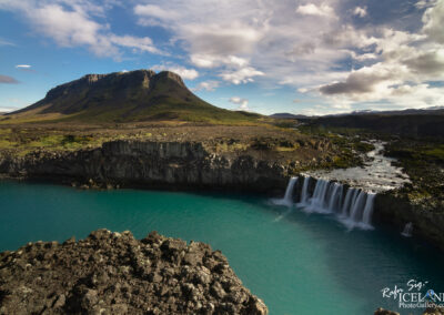 Waterfall flowing gracefully, framed by the majestic Búrfell mountain, representing Iceland's picturesque scenery.