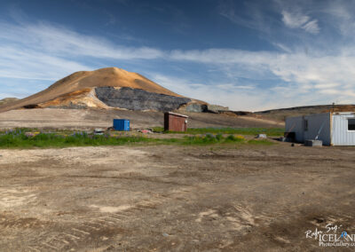 A winding dirt road surrounded by greenery, leading into the distance under a clear blue sky.