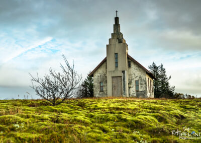 A historic church stands proudly on a grassy hill, offering a picturesque view of the landscape.